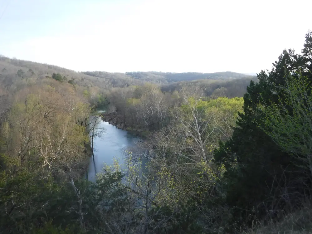 The Buffalo River winding between wooded banks speckled with the first new leaves and blossoms of spring