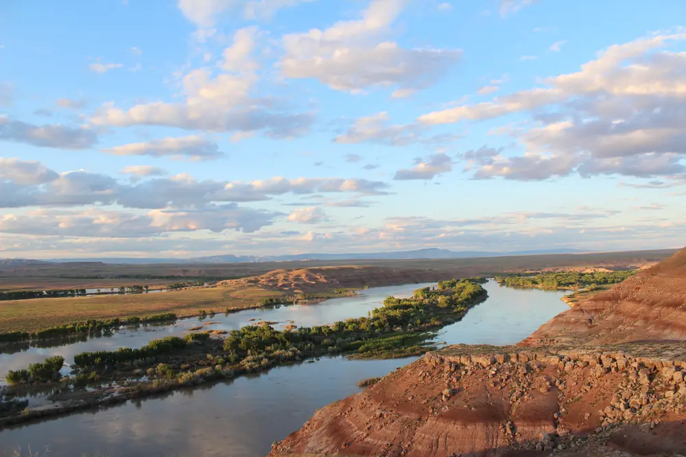 The Green River at sunset, a broad band of calm water reflecting orange light between low banks and trees